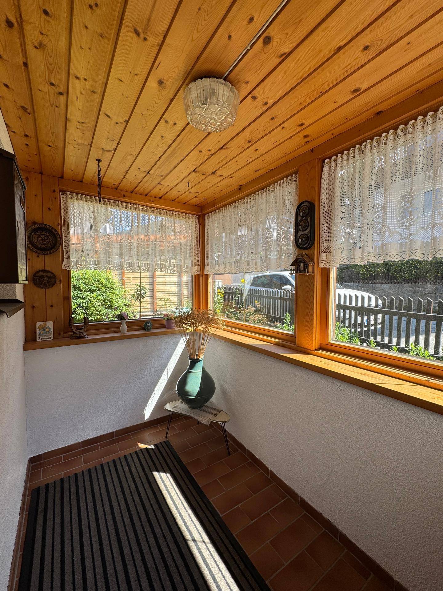 Gemütlicher Eingangsbereich mit Holzverkleidung an Decke und Wänden sowie Terrakottafliesen.