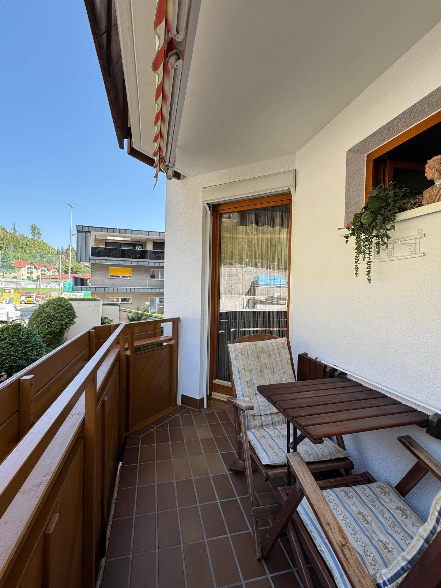 Kleiner Balkon mit Holztisch und Stühlen, ideal für entspannte Stunden im Freien.