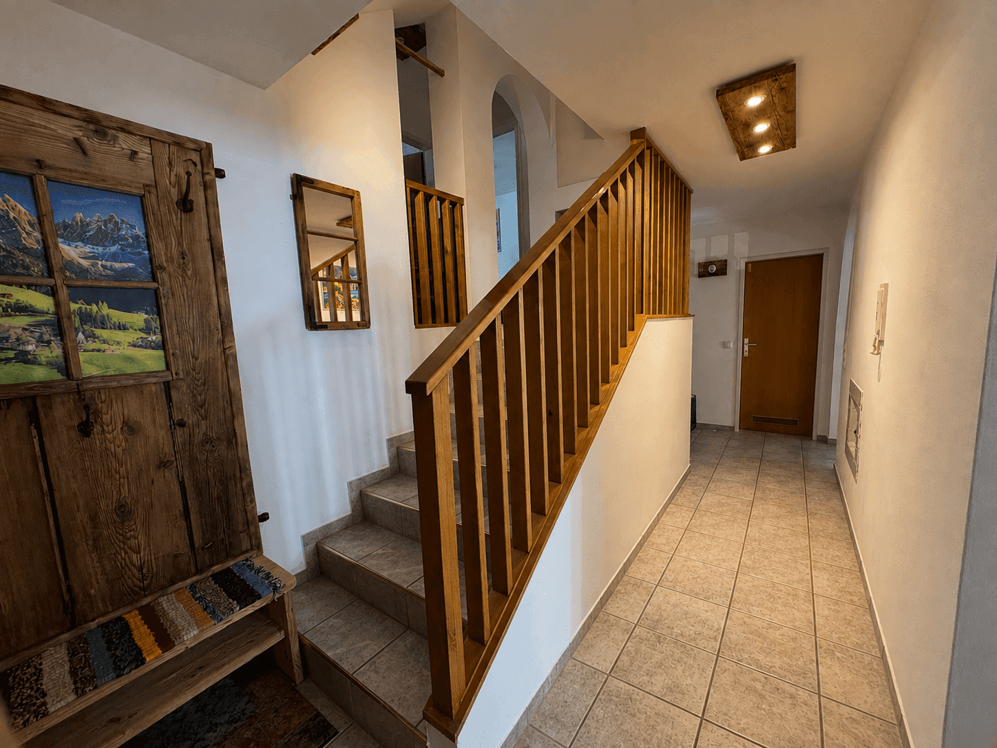 Geräumiger Flur mit Holztreppe, Fliesenboden und rustikalen Holzelementen.