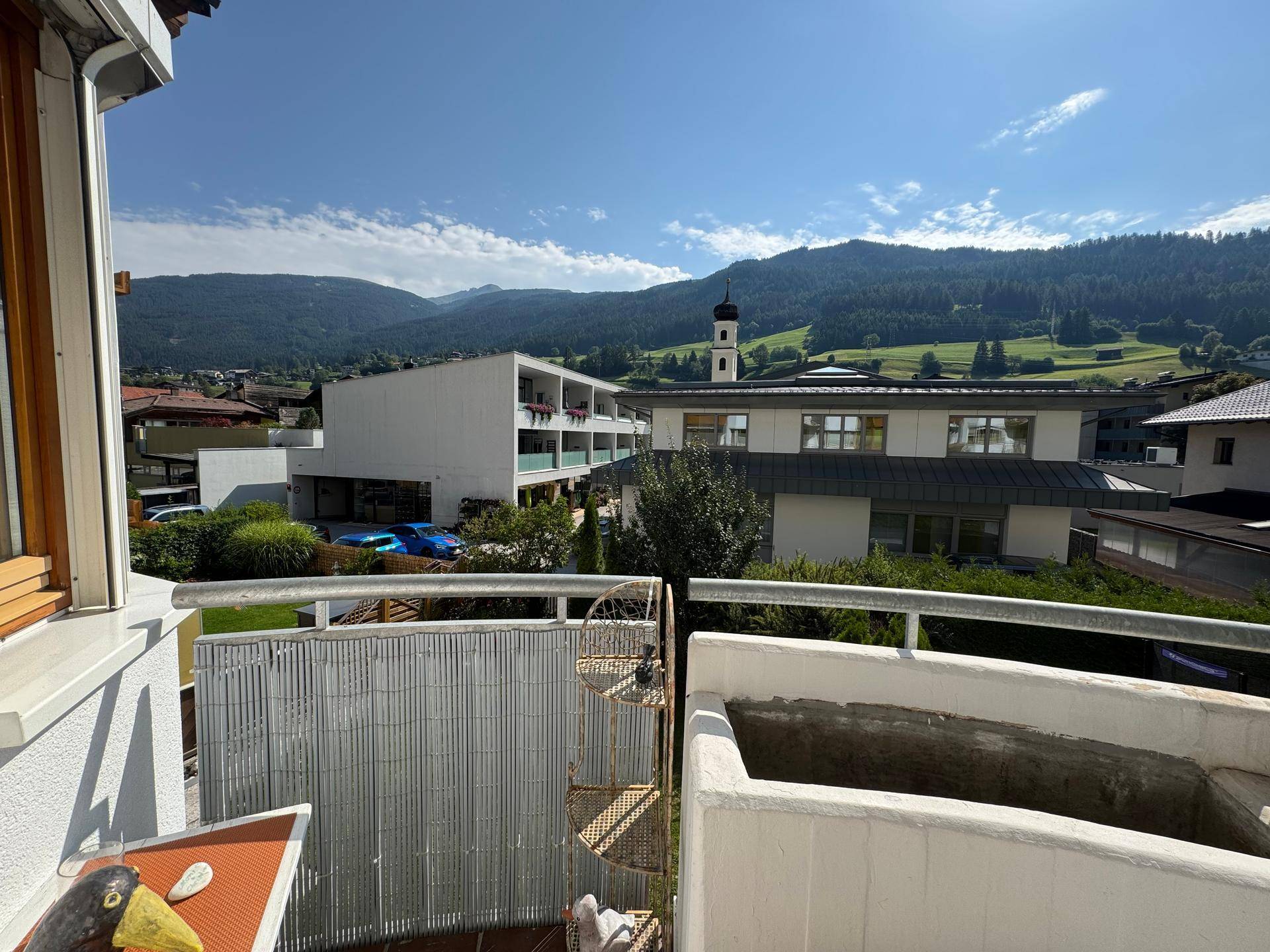 Balkon mit Panoramablick auf die Berge und den Kirchturm der nahegelegenen Ortschaft.