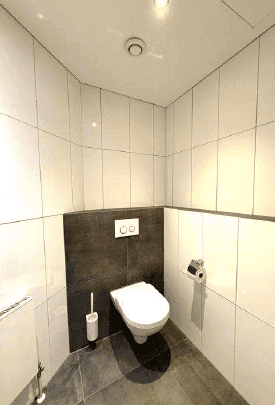 Saubere und moderne Toilette mit weißen Fliesen und einer dunklen Akzentwand, gut beleuchtet.