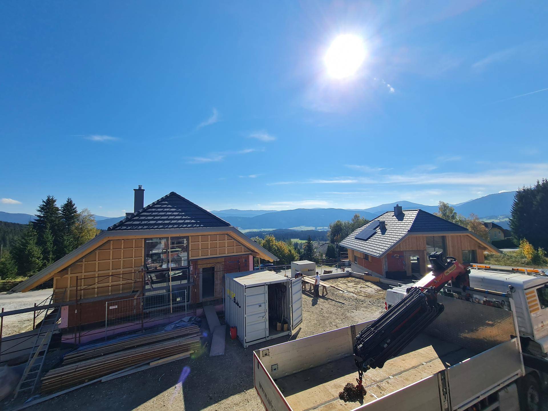 Luftaufnahme von Häusern im Bau an einem sonnigen Tag mit Bergblick.