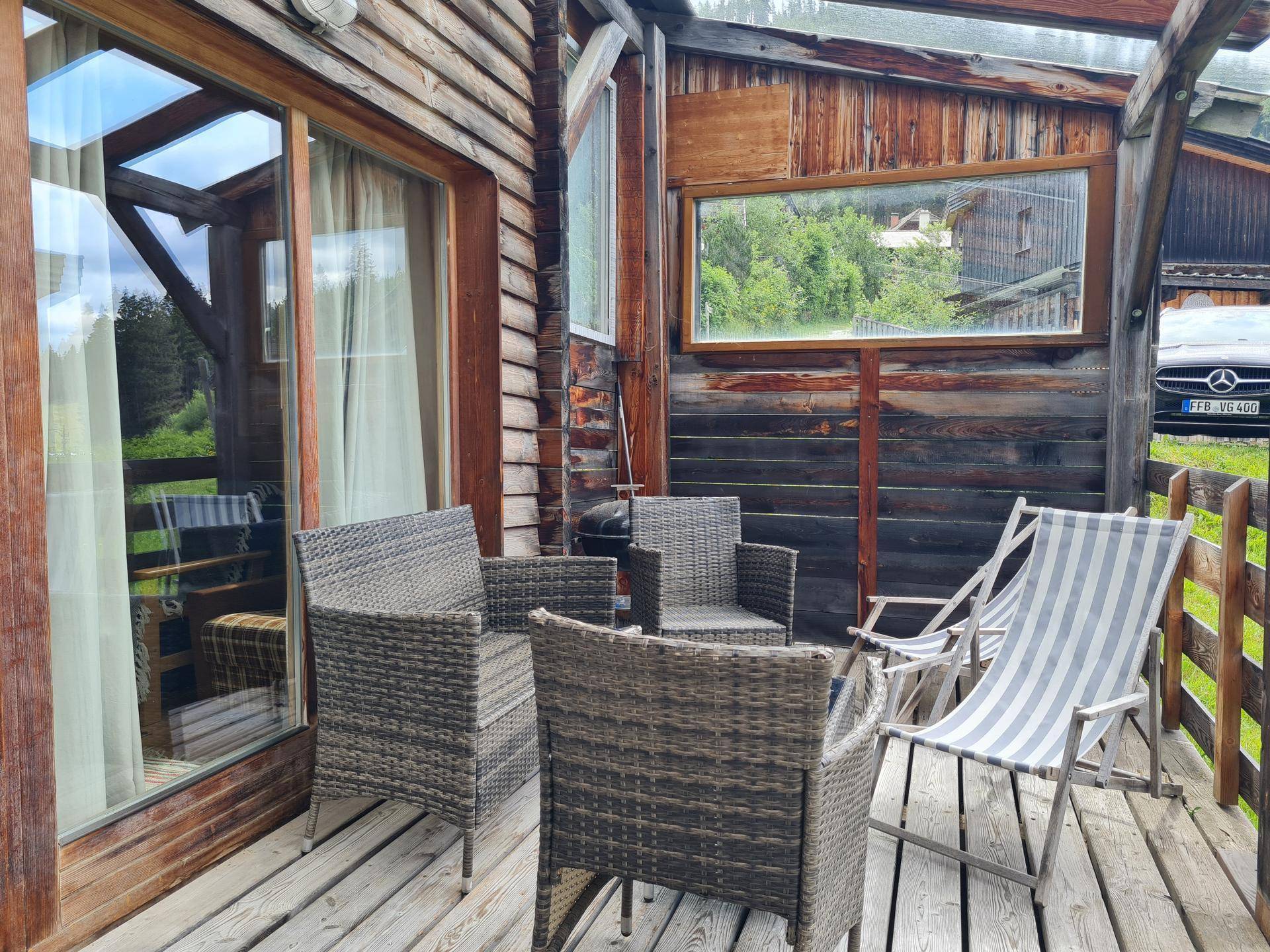 Gemütliche Holzterrasse mit Korbmöbeln und Blick ins Grüne, ideal zum Entspannen.