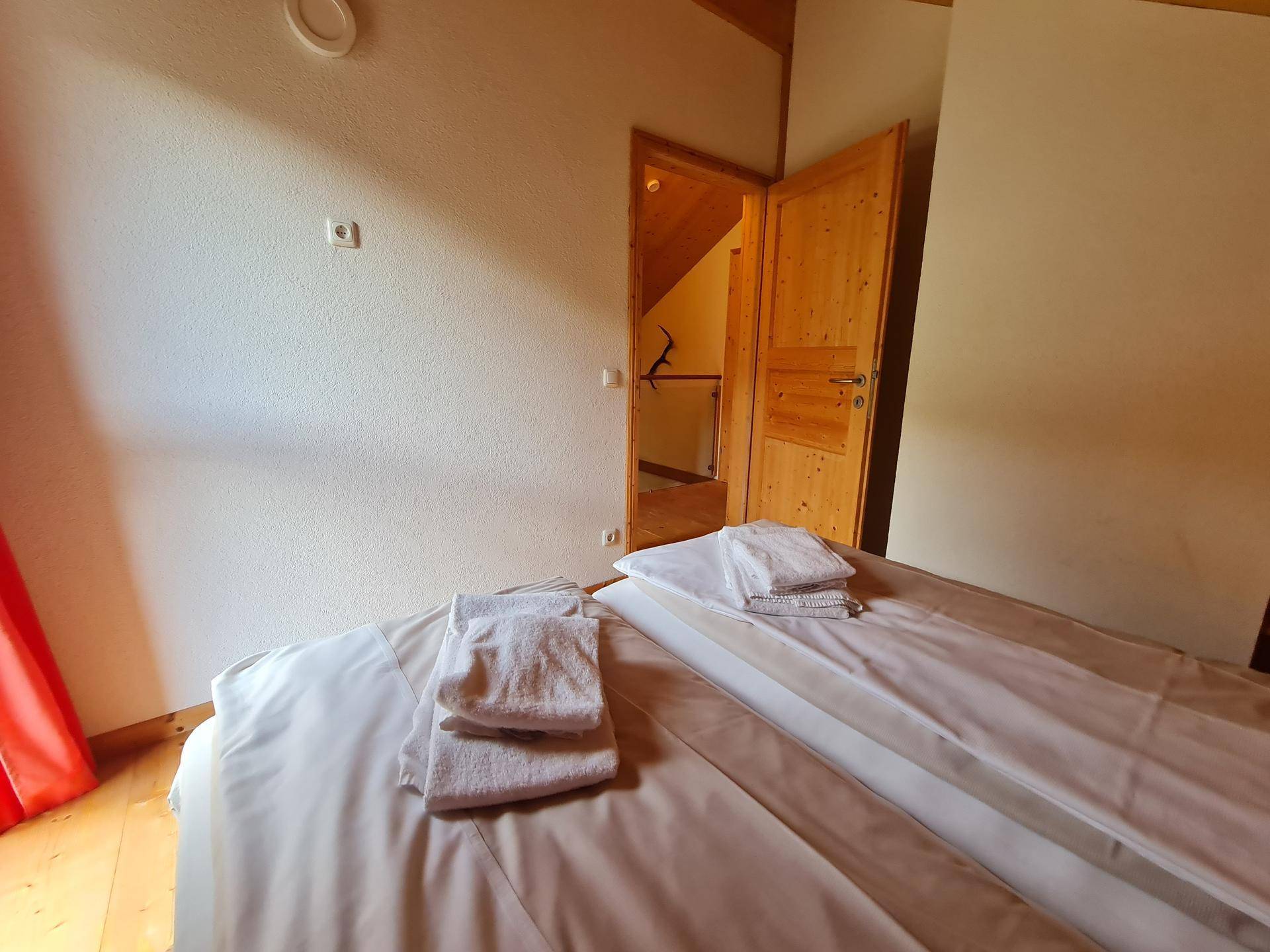 Helles Schlafzimmer mit Doppelbett, Holzboden und weiß gestrichenen Wänden im Dachgeschoss.