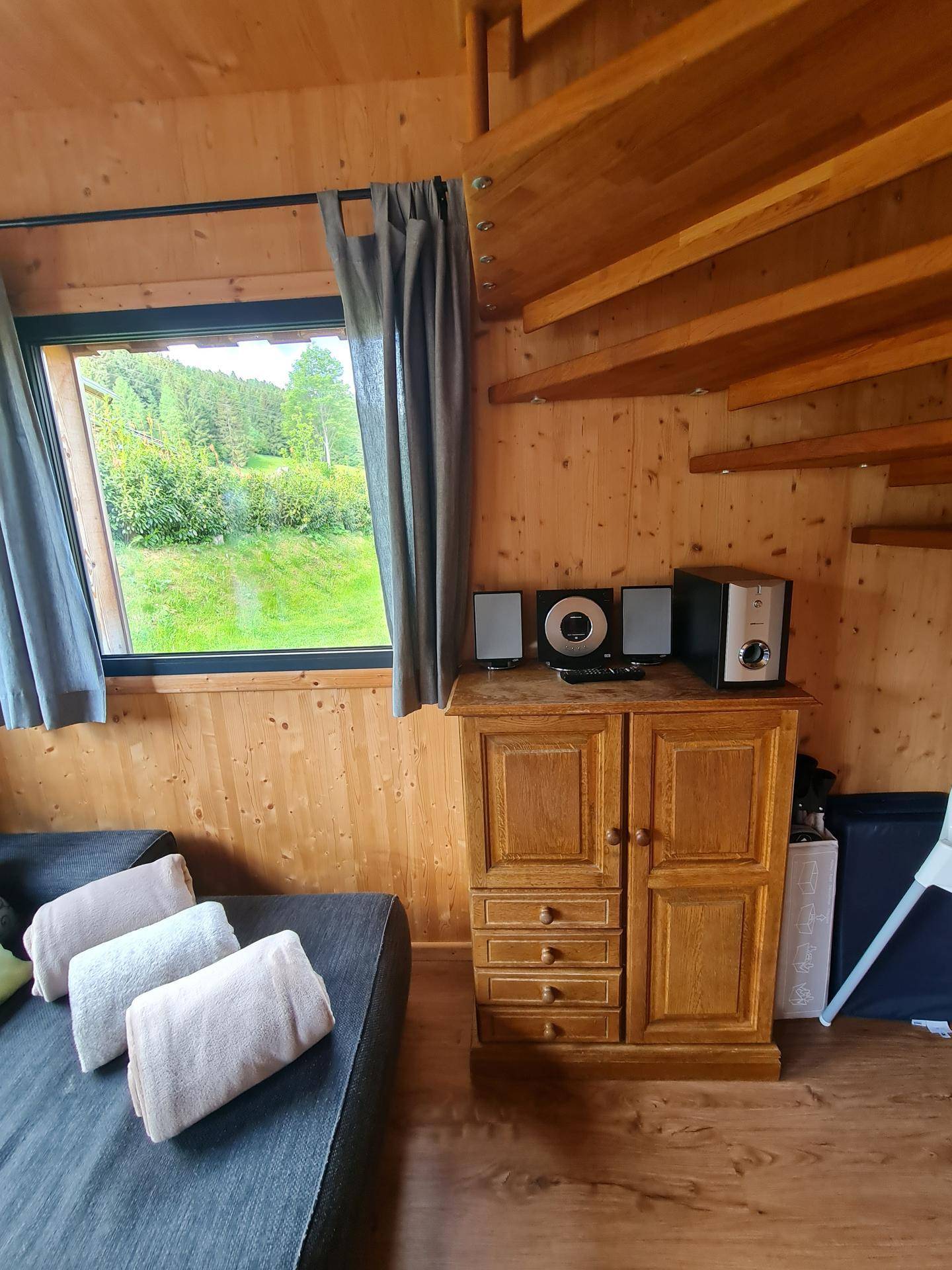 Wohnbereich mit Holzwänden, Holzboden und Blick auf die grüne Natur.