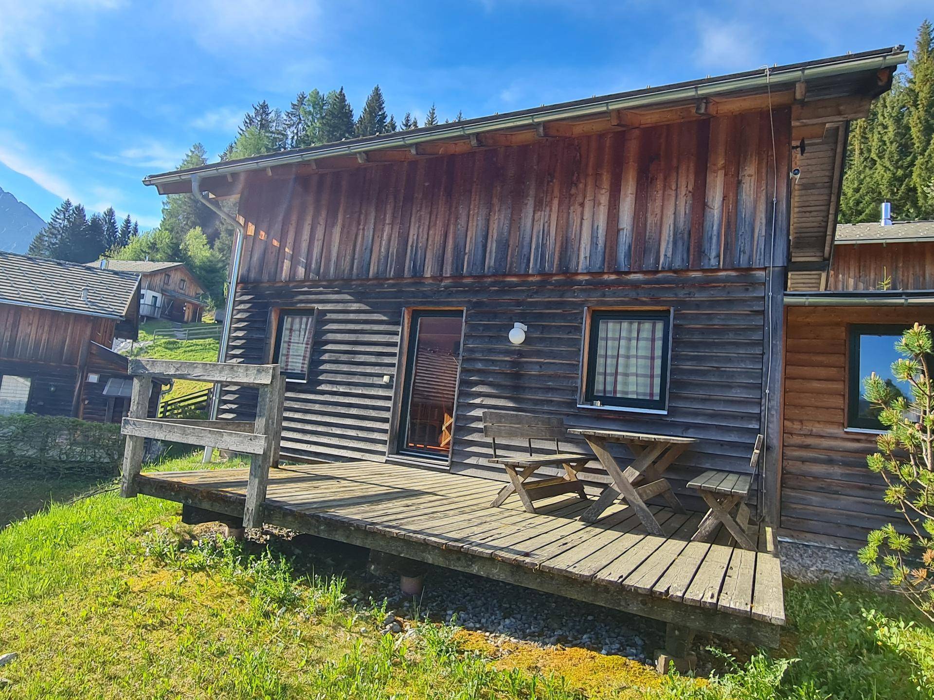 Gemütliche Holzterrasse mit Sitzgelegenheiten vor dem Chalet, umgeben von Natur.