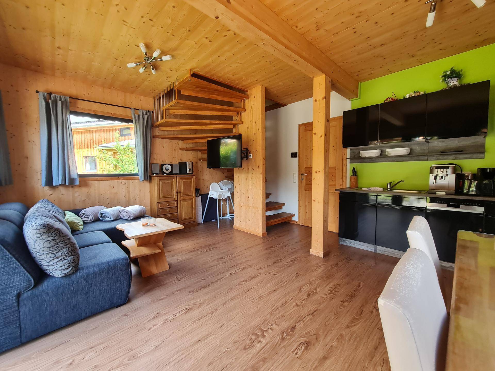 Geräumiger Wohnbereich mit bequemer Couch, Holzvertäfelung und Wendeltreppe in hellem Holz.