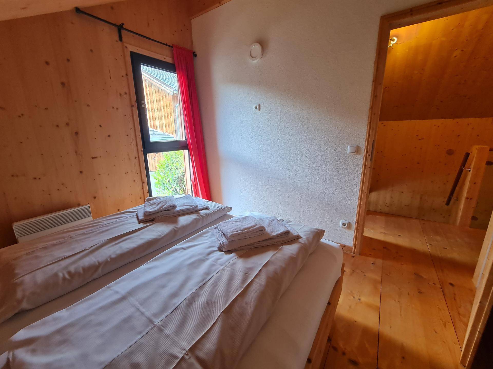 Schlafzimmer mit Doppelbett und Zugang zu einem weiteren Raum im Dachgeschoss.