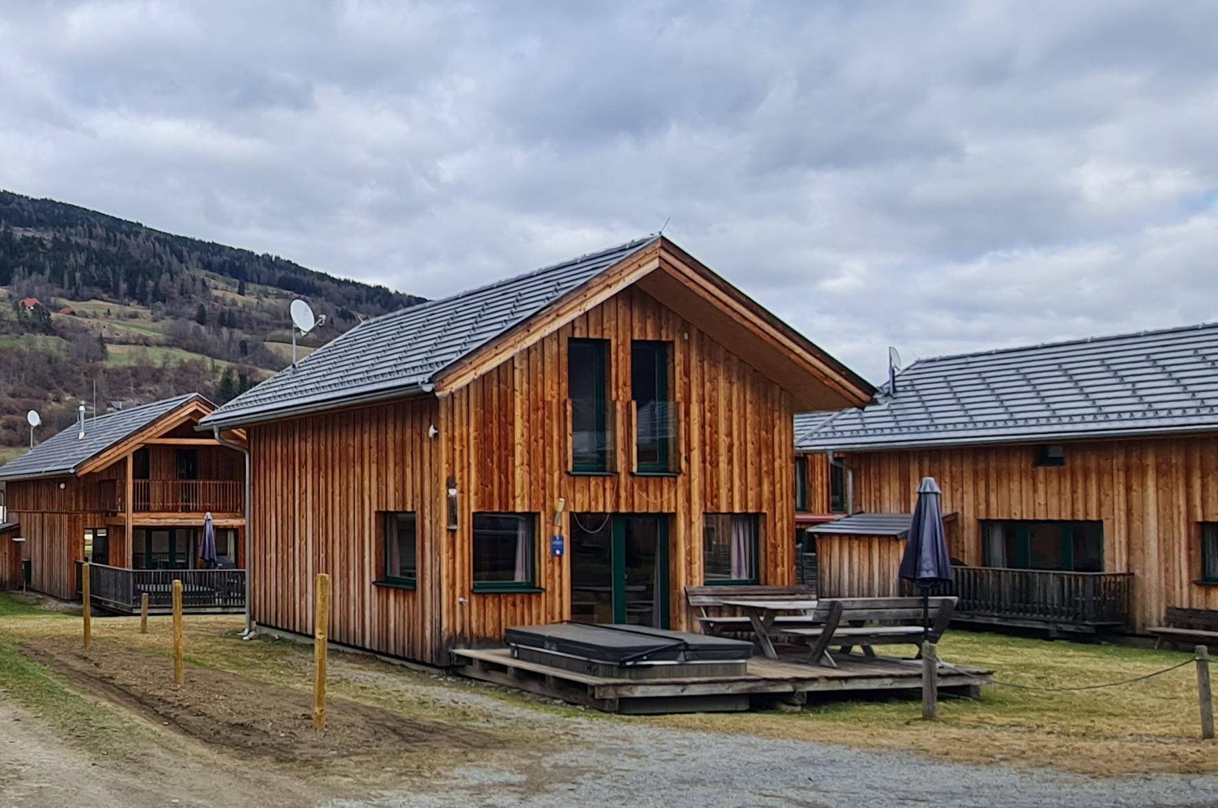 Ferienhäuser aus Holz mit Satteldach und Bergblick in einer ländlichen Umgebung.