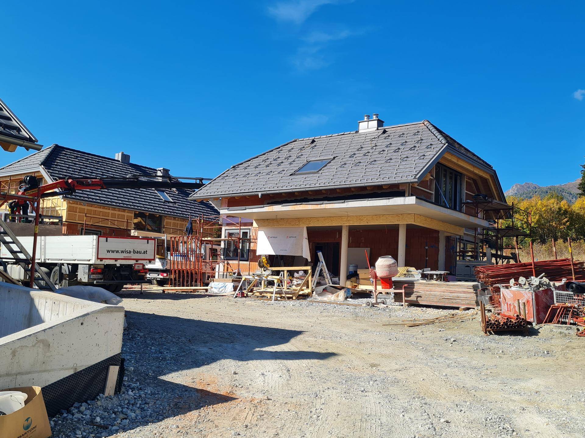 Haus im Bau mit Gerüst und Baumaterialien, zeigt den Fortschritt der Außenarbeiten.