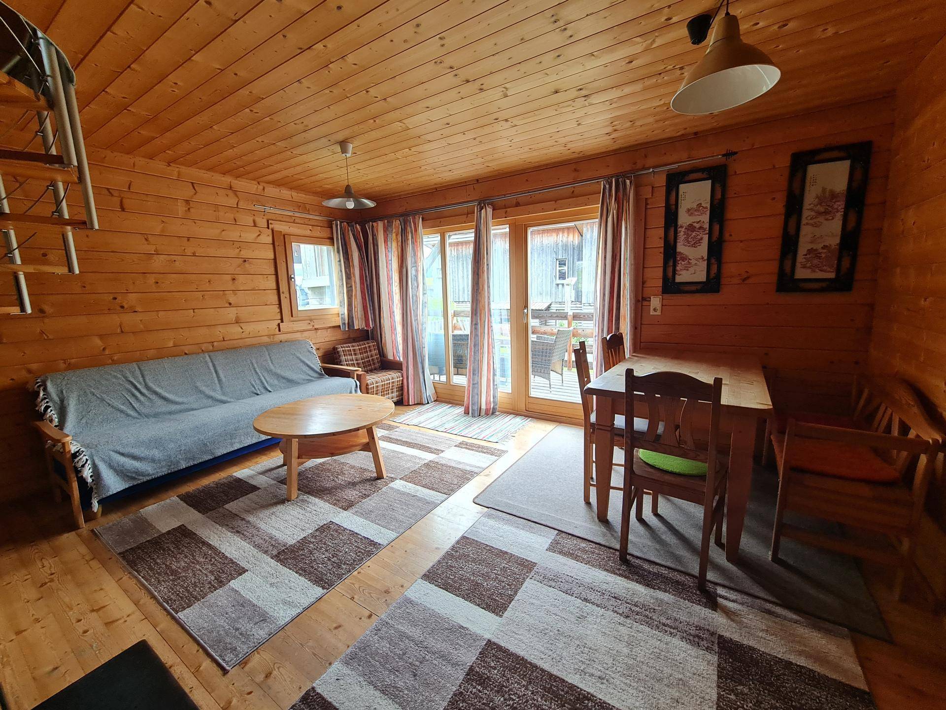 Heller Wohn-Essbereich mit Holzboden, bequemer Couch und Zugang zu einer Außenterrasse.