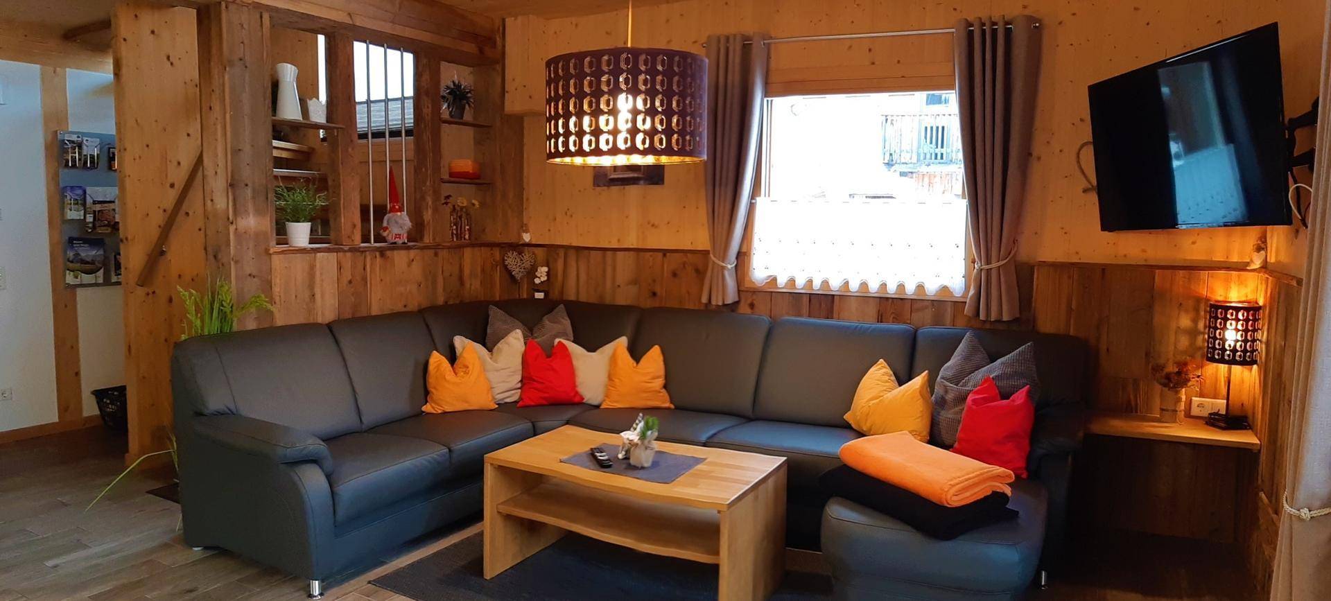 Gemütliches Wohnzimmer im alpinen Stil mit großer Eckcouch und Holzwänden.