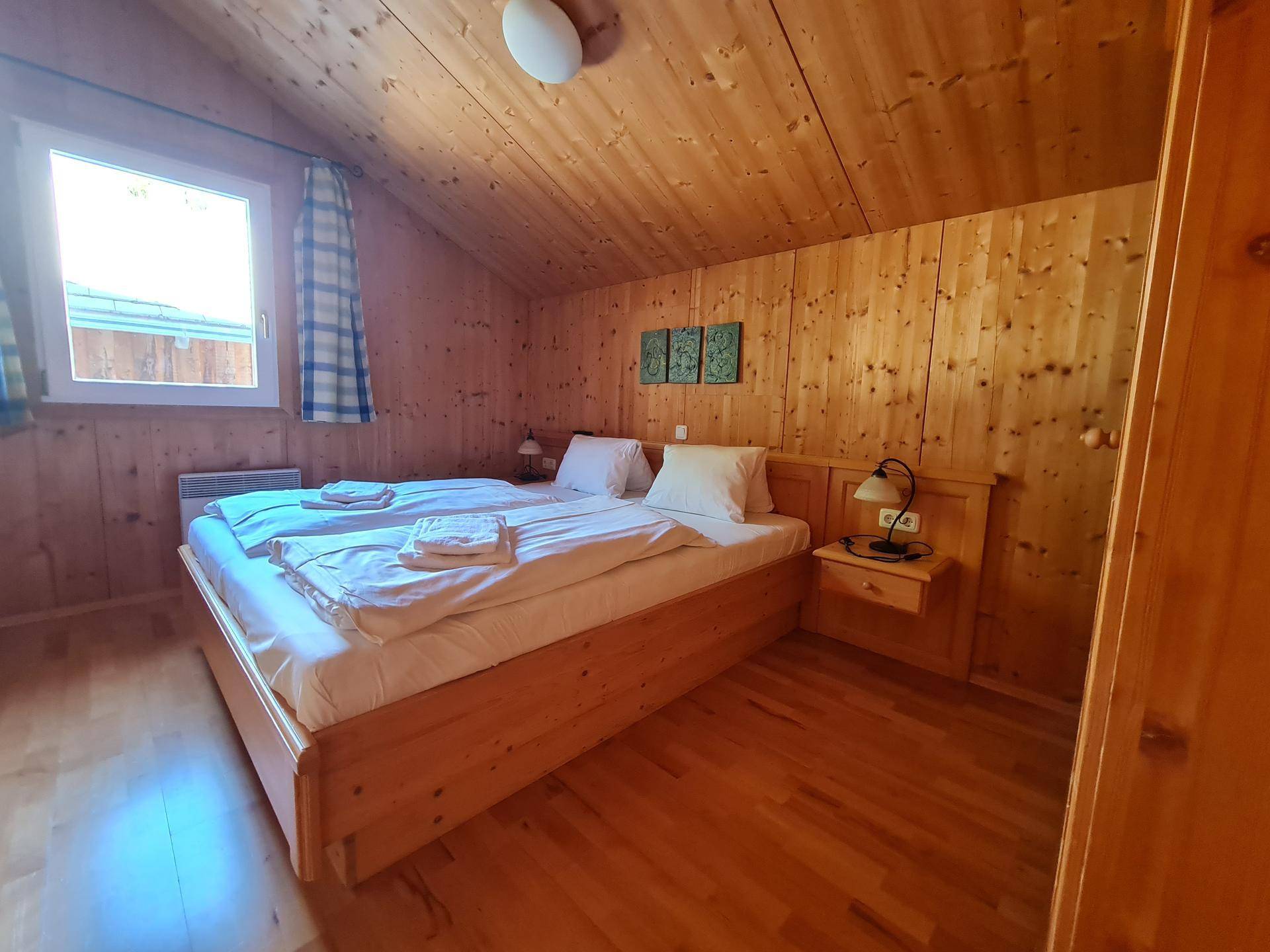 Schlafzimmer im Dachgeschoss mit Holzwänden, Holzboden und Doppelbett.