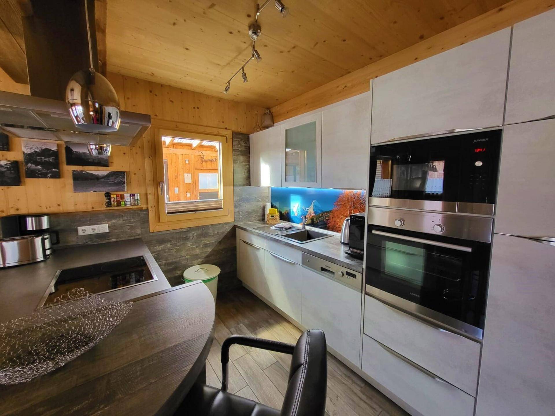 Stilvolle Küche mit modernen Geräten, Holzwänden und einem Fenster mit Ausblick.