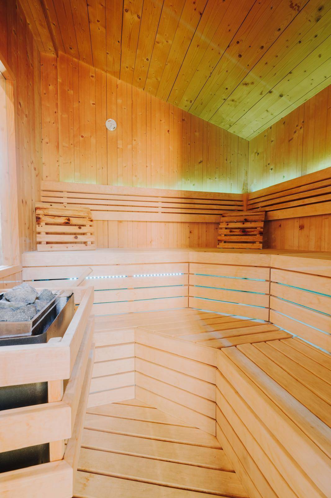 Geräumige Holzsauna mit mehreren Bänken und stimmungsvoller Beleuchtung für Entspannung.