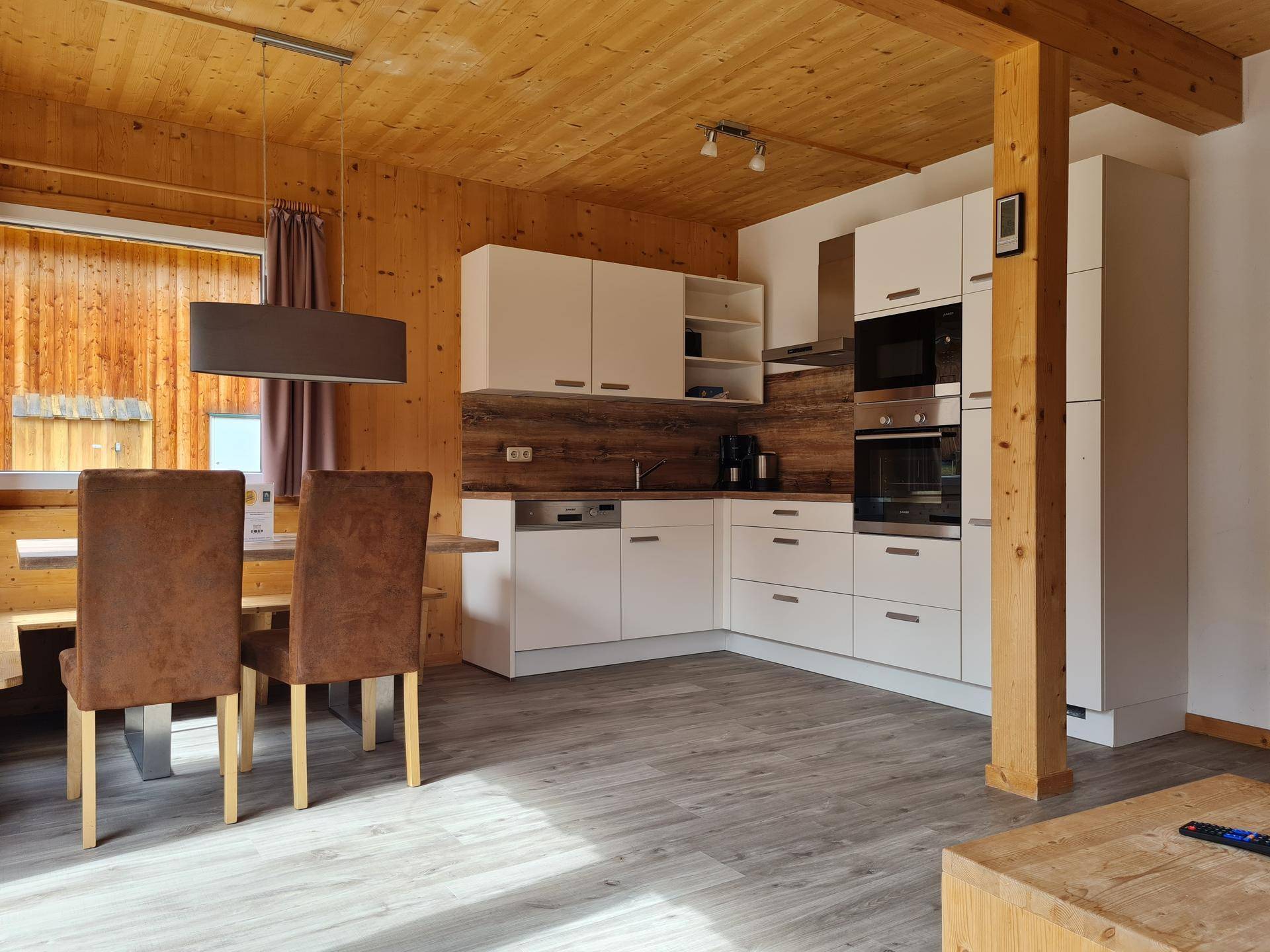 Moderne Einbauküche mit weißen Schränken und integrierten Geräten in einem Holzhaus.