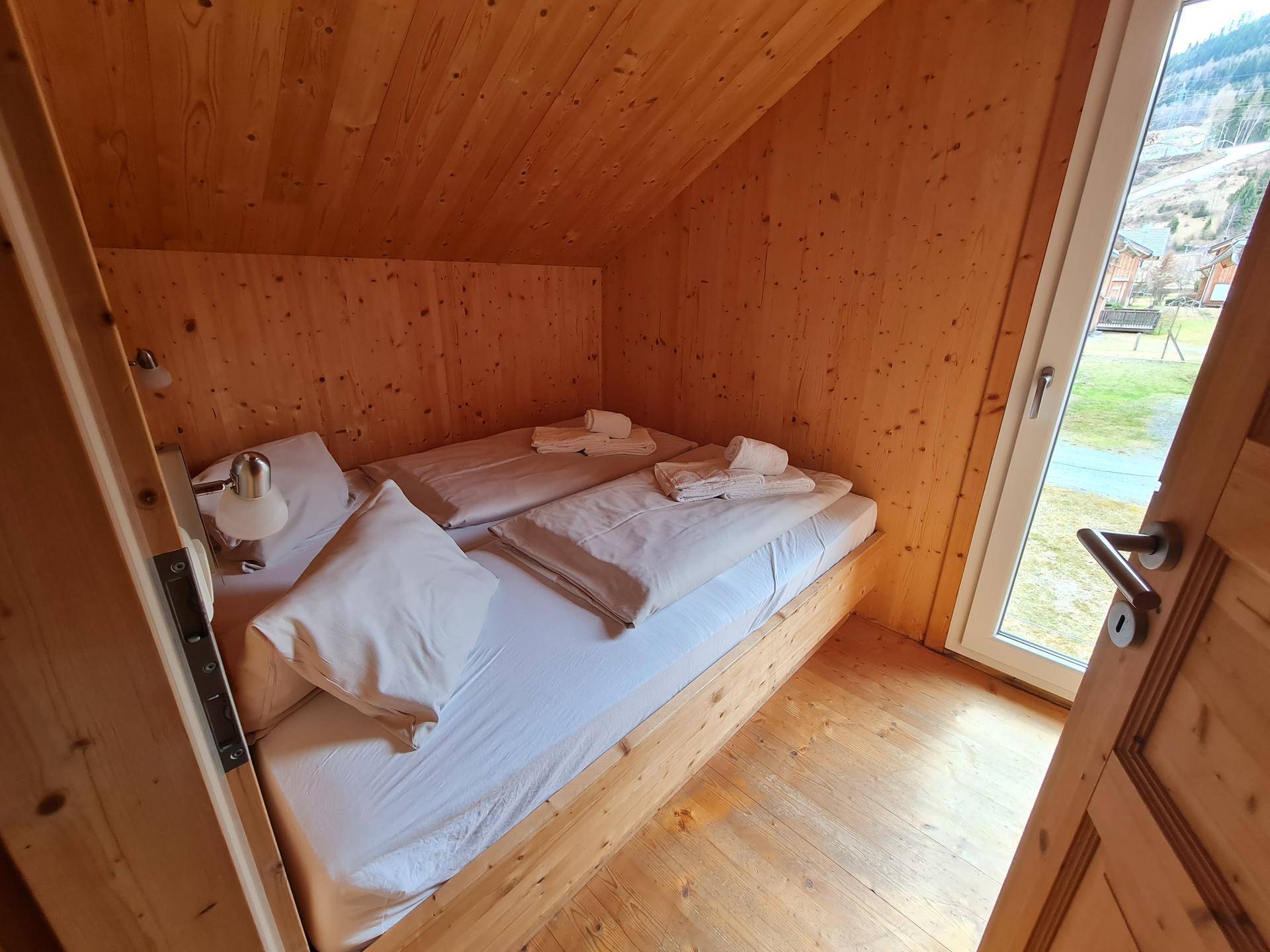 Kleines Schlafzimmer mit zwei Einzelbetten, Holzvertäfelung und Dachschräge.