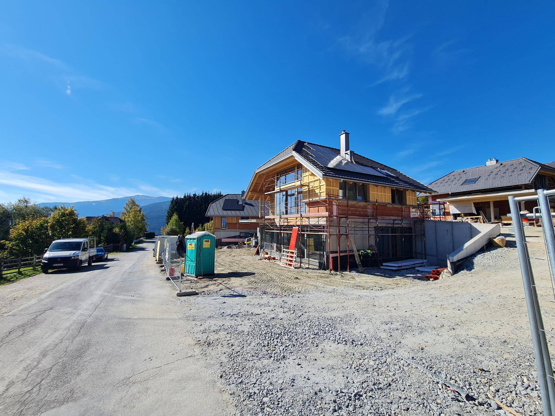 Haus im Bau von der Straße aus gesehen, mit Gerüst und Baustelleneinrichtung.