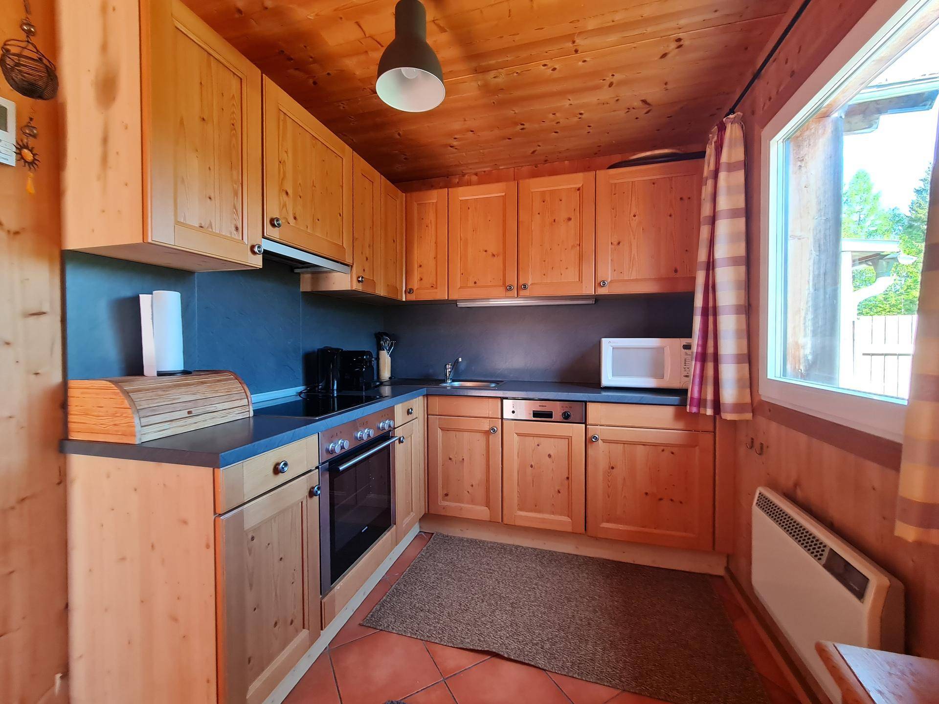 Funktionale Küche im Landhausstil mit Holzschränken, Fliesenboden und Fensterblick.