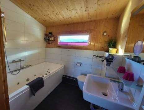 Modernes Badezimmer mit Whirlpool-Badewanne, Waschbecken und Holzwänden.