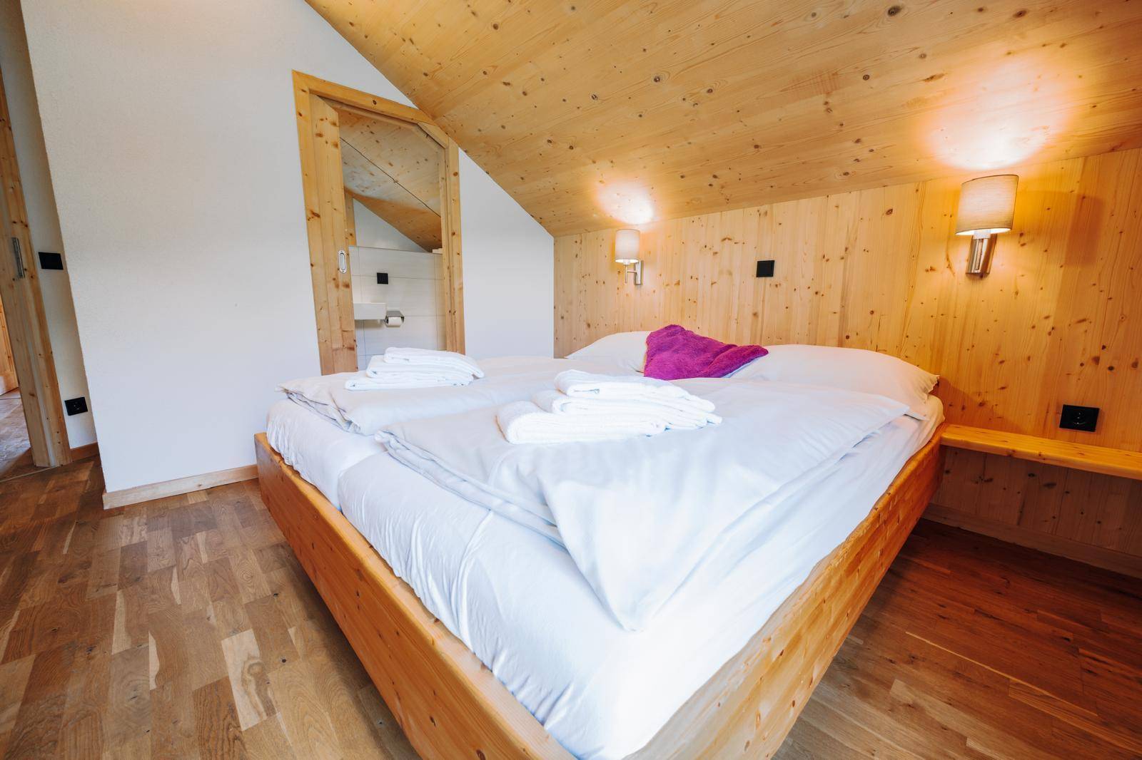 Komfortables Schlafzimmer mit Doppelbett, Holzwänden und schrägen Decken.
