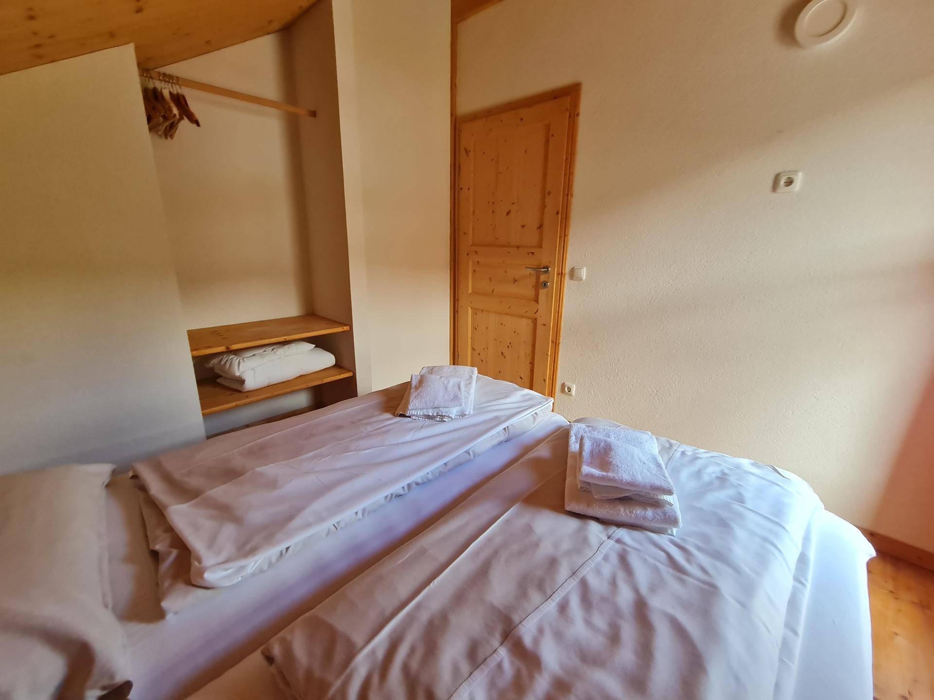 Helles Schlafzimmer mit Holzboden, Holzwänden und Blick auf die umliegende Landschaft.