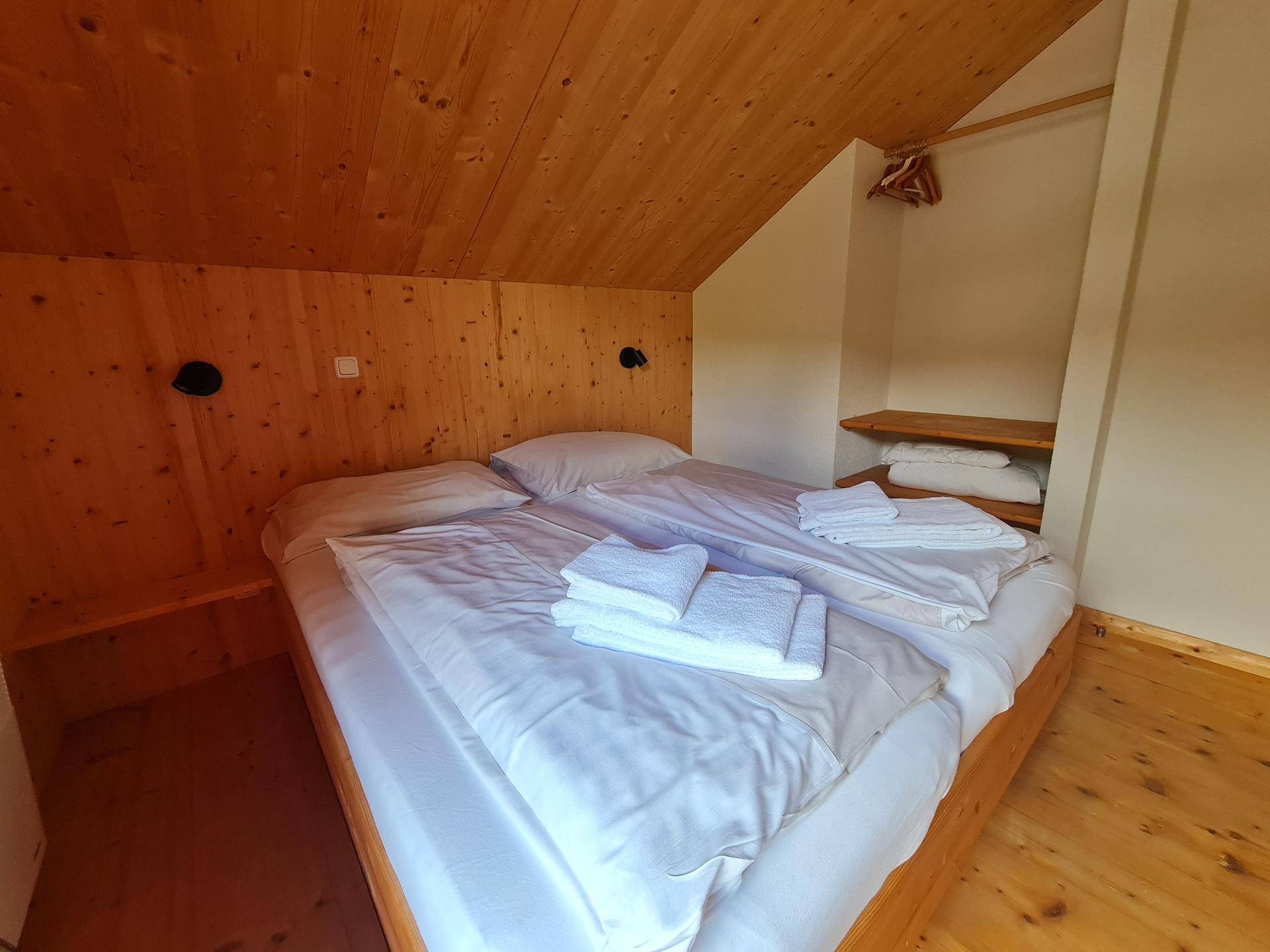 Gemütliches Schlafzimmer im Dachgeschoss mit Holzwänden, Holzboden und zwei Einzelbetten.