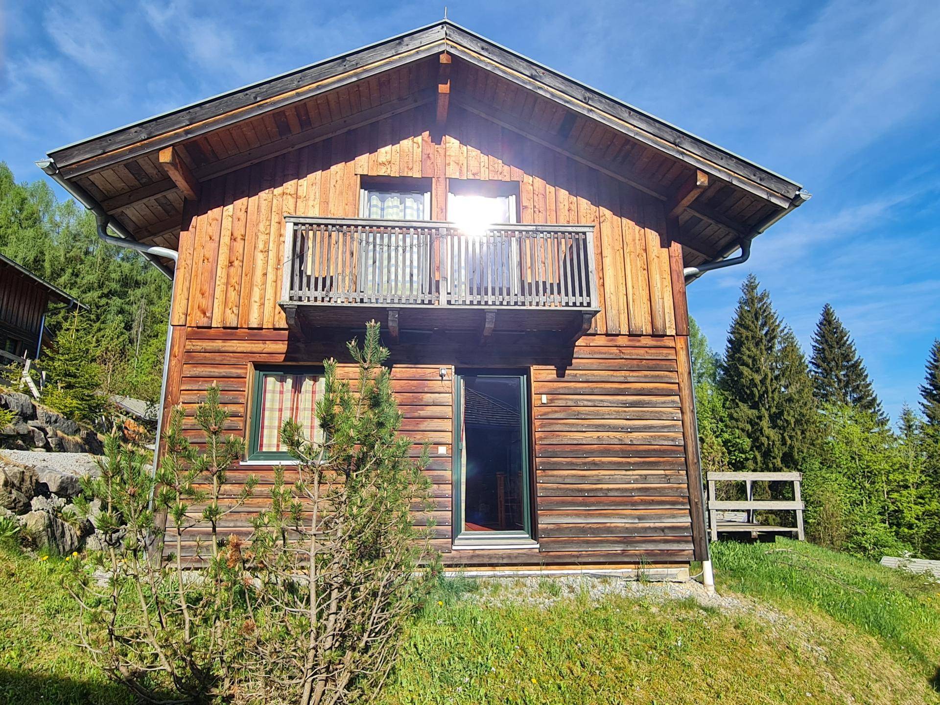Charmantes Holzchalet mit traditionellem Balkon und Blick auf die umliegende Berglandschaft.
