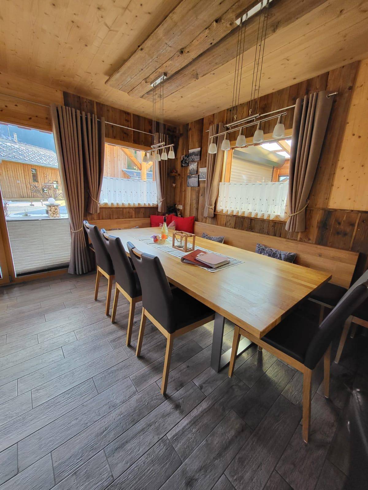 Heller Essbereich mit Holzwänden und -decken, großem Holztisch und bequemen Stühlen.