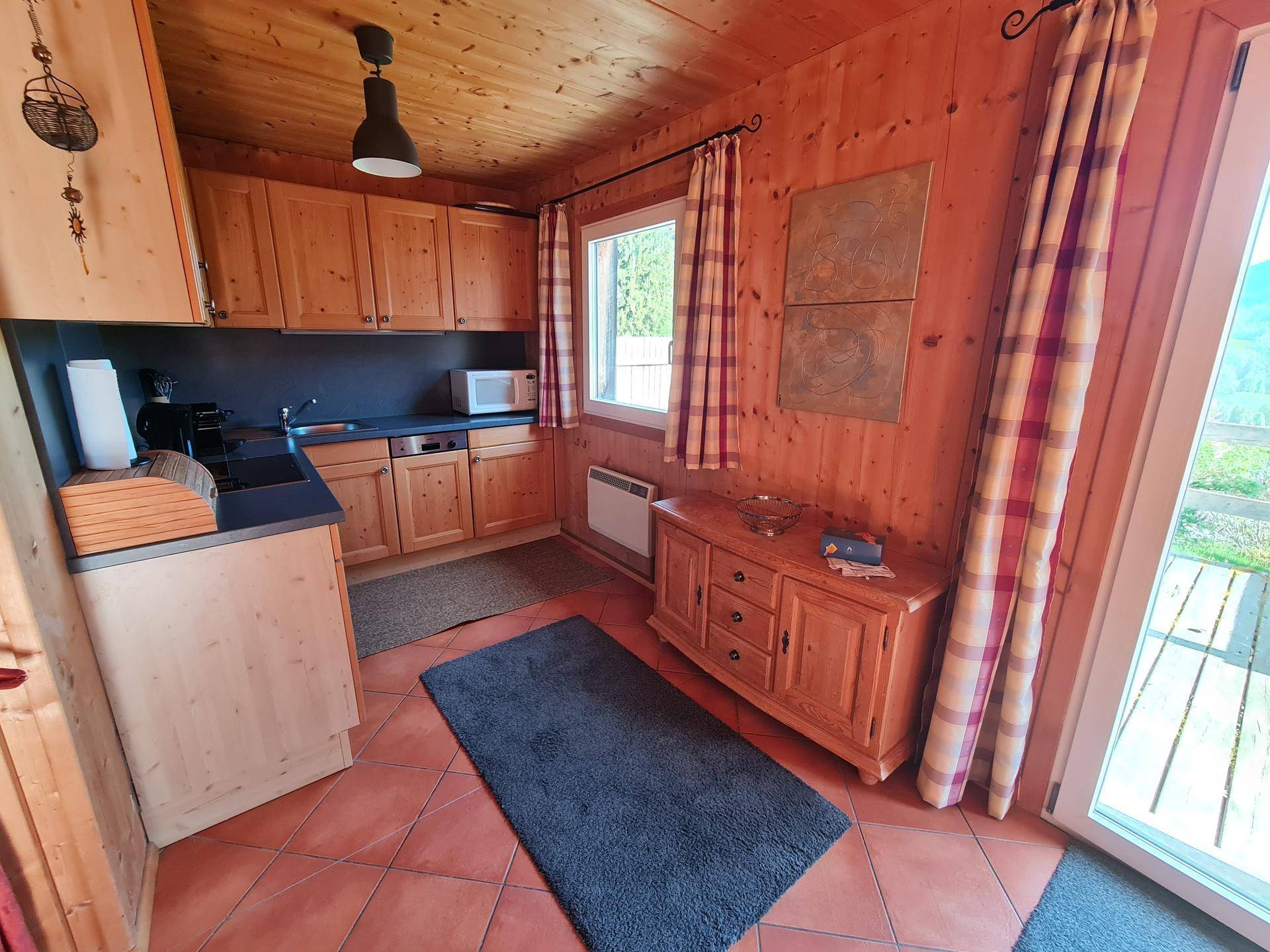 Helle Küche mit Holzmöbeln, Terracottaboden und Zugang zur Außenterrasse.