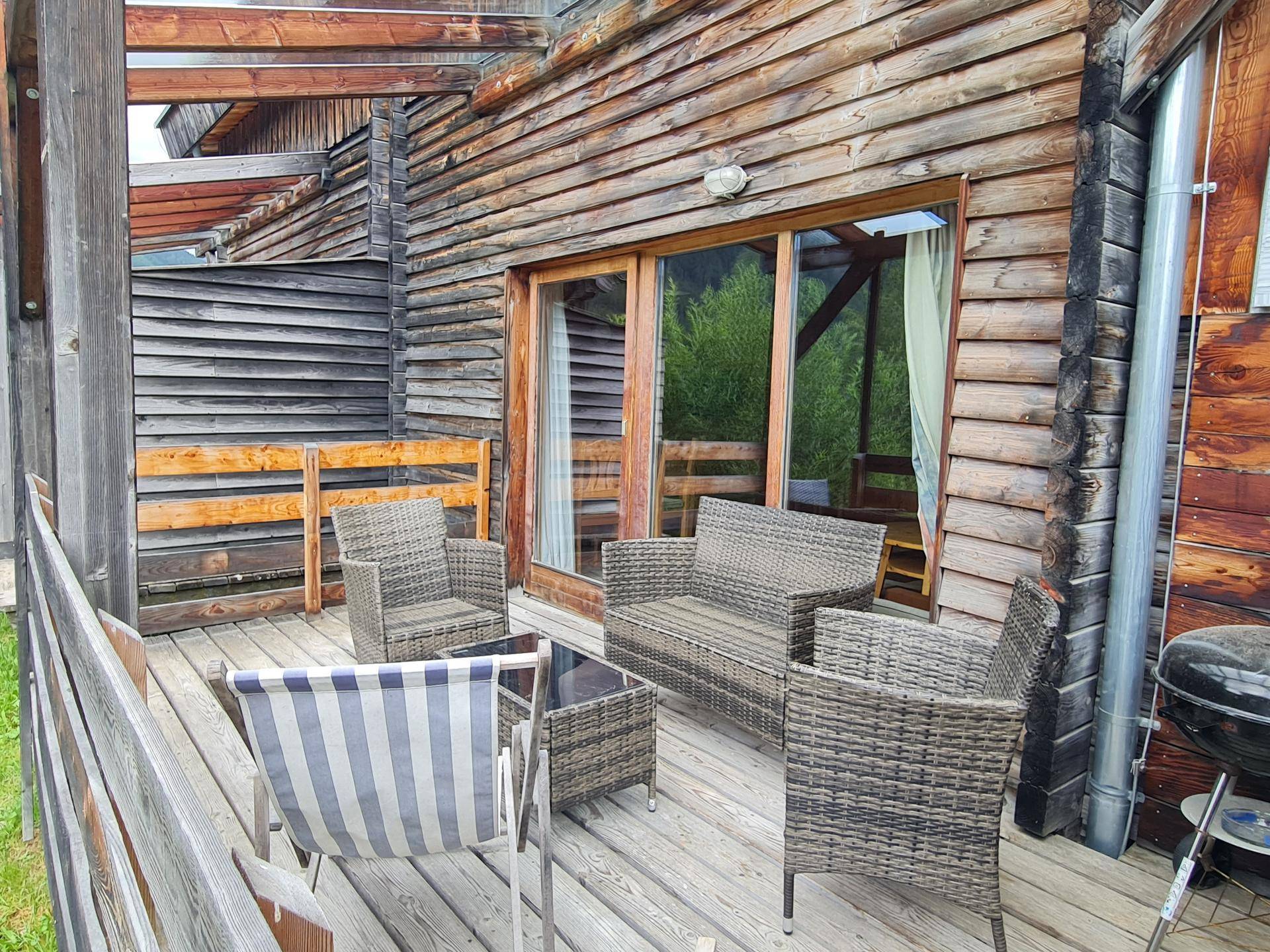 Geräumige Holzterrasse mit bequemen Sitzgelegenheiten und Grill für gesellige Stunden im Freien.