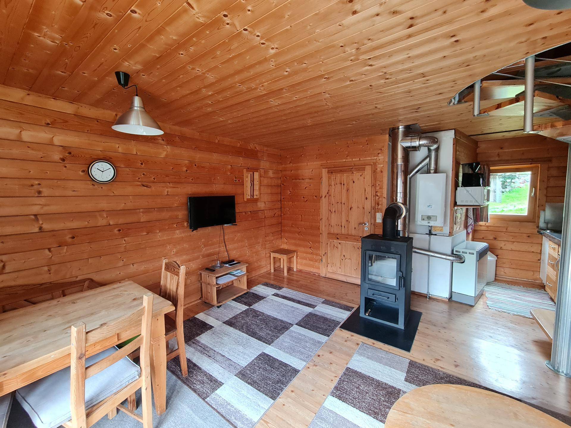 Gemütlicher Wohn-Essbereich mit Holztäfelung, Kaminofen und rustikalem Esstisch.