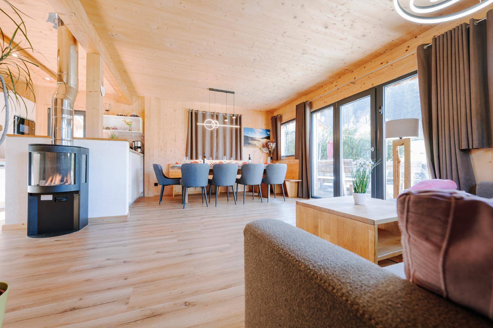 Heller Wohn- und Essbereich mit Holzboden, Kamin und großzügigen Fensterfronten.