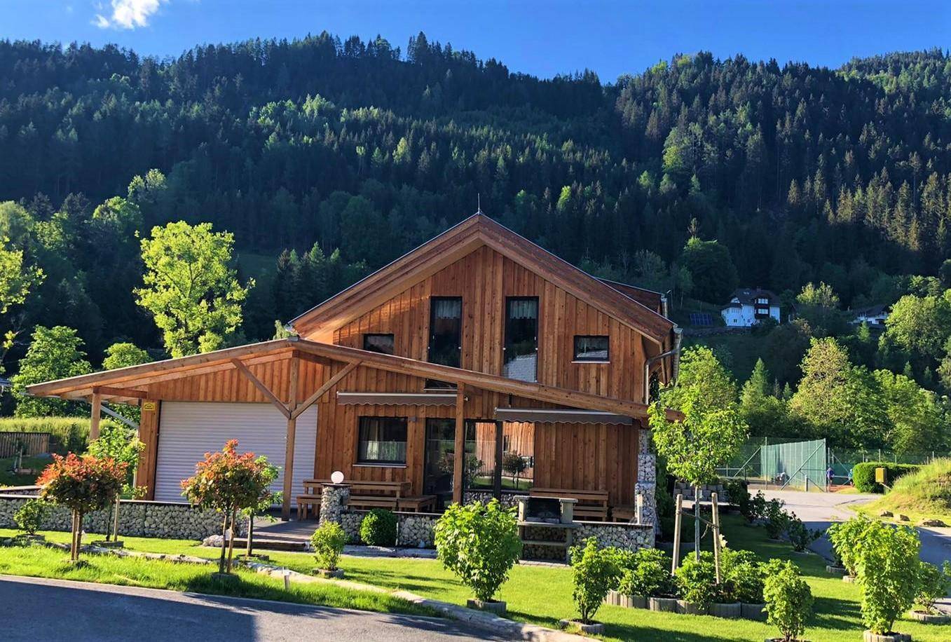 Modernes Holzhaus mit weitläufigem Garten und Blick auf die umliegende Berglandschaft.
