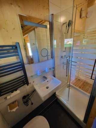 Kompaktes Badezimmer mit Duschkabine, Waschbecken und beheiztem Handtuchhalter.