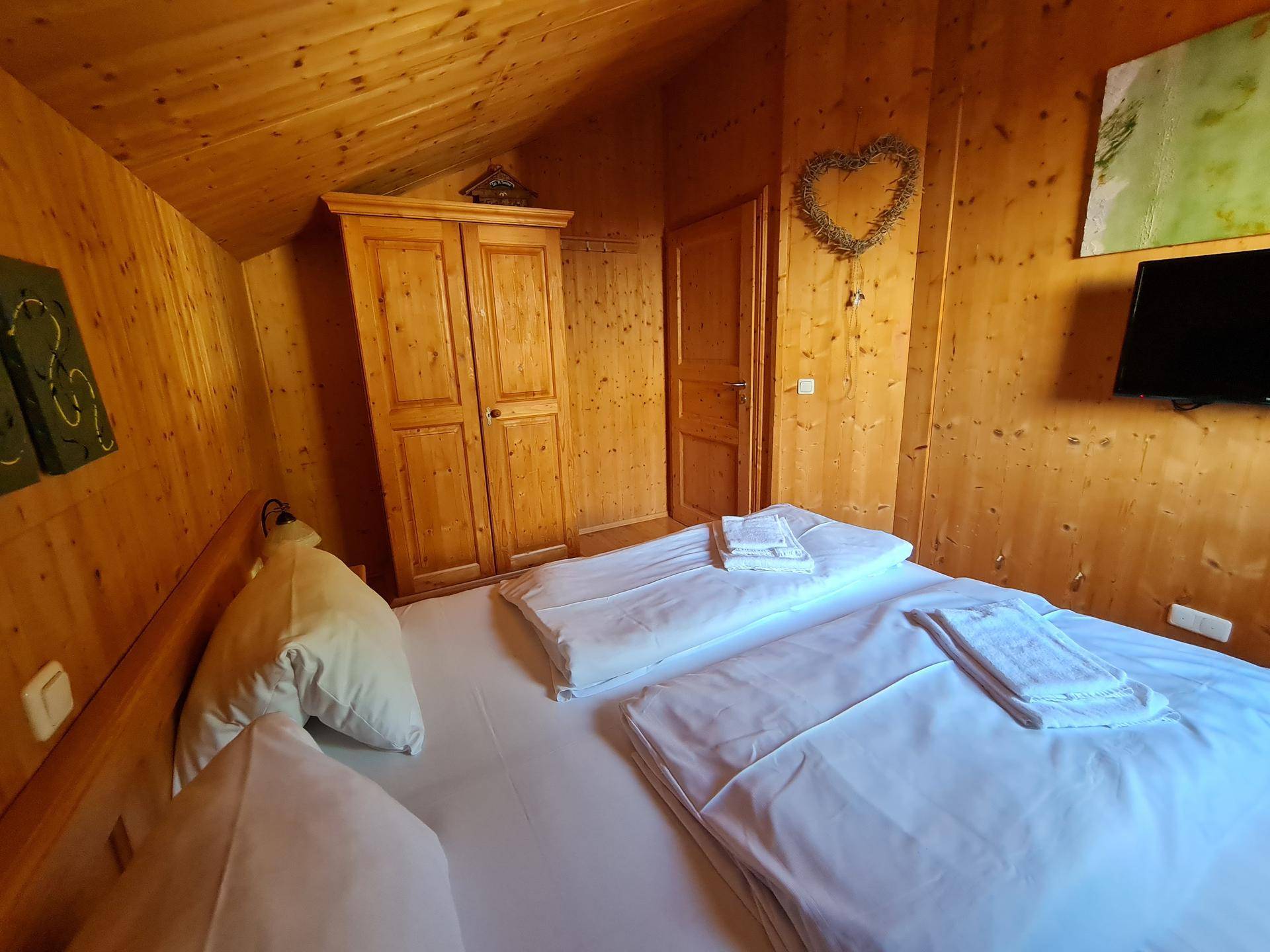 Gemütliches Schlafzimmer mit Holzwänden, Holzboden und Kleiderschrank.