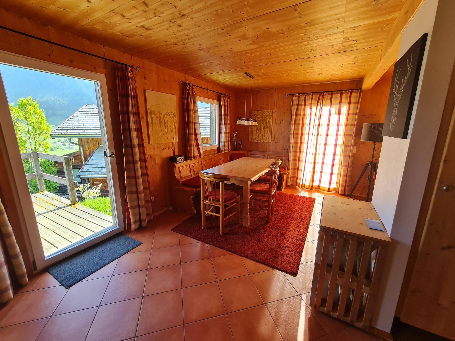 Heller Essbereich mit Holztisch, Eckbank und großem Fenster mit Blick ins Grüne.