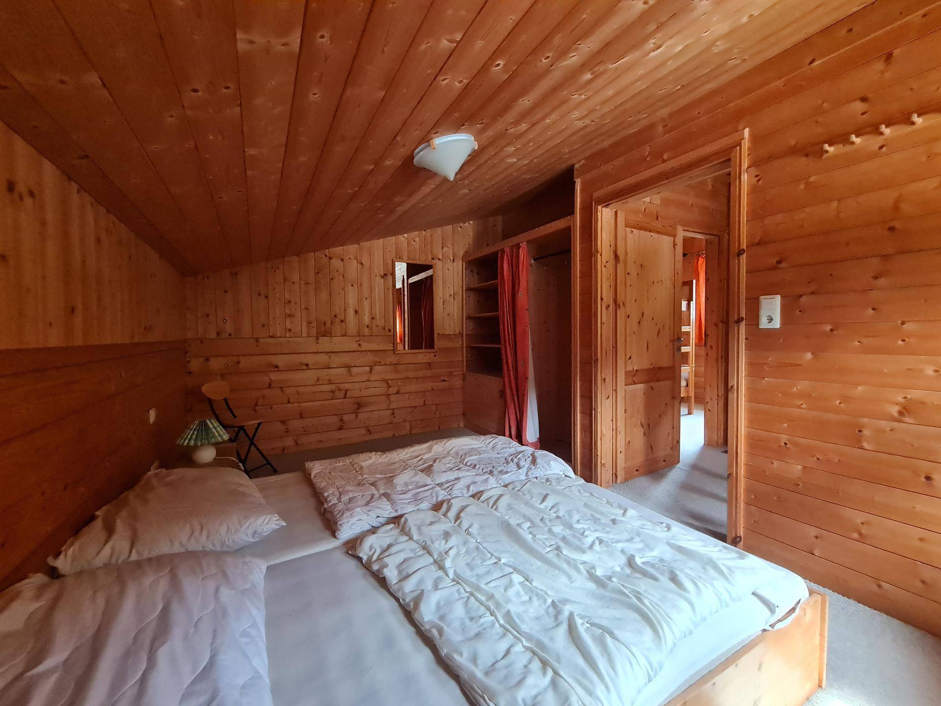 Gemütliches Schlafzimmer mit Doppelbett, Holztäfelung und Dachschräge, hell und einladend.