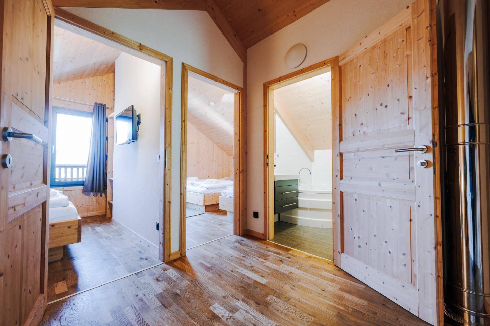 Heller Flur mit Holzboden und Zugang zu mehreren Schlafzimmern und einem Badezimmer.