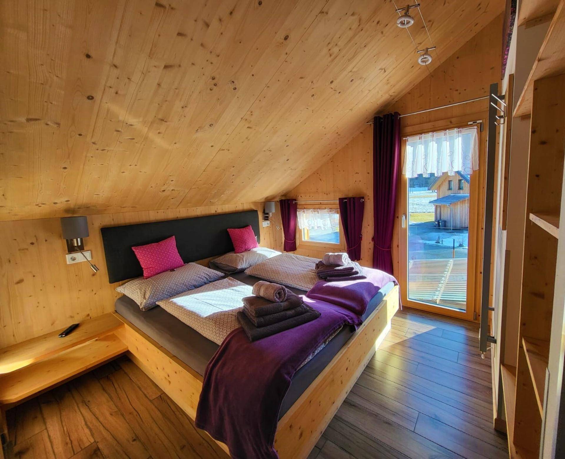 Komfortables Schlafzimmer im Dachgeschoss mit Holzwänden, Doppelbett und viel Tageslicht.
