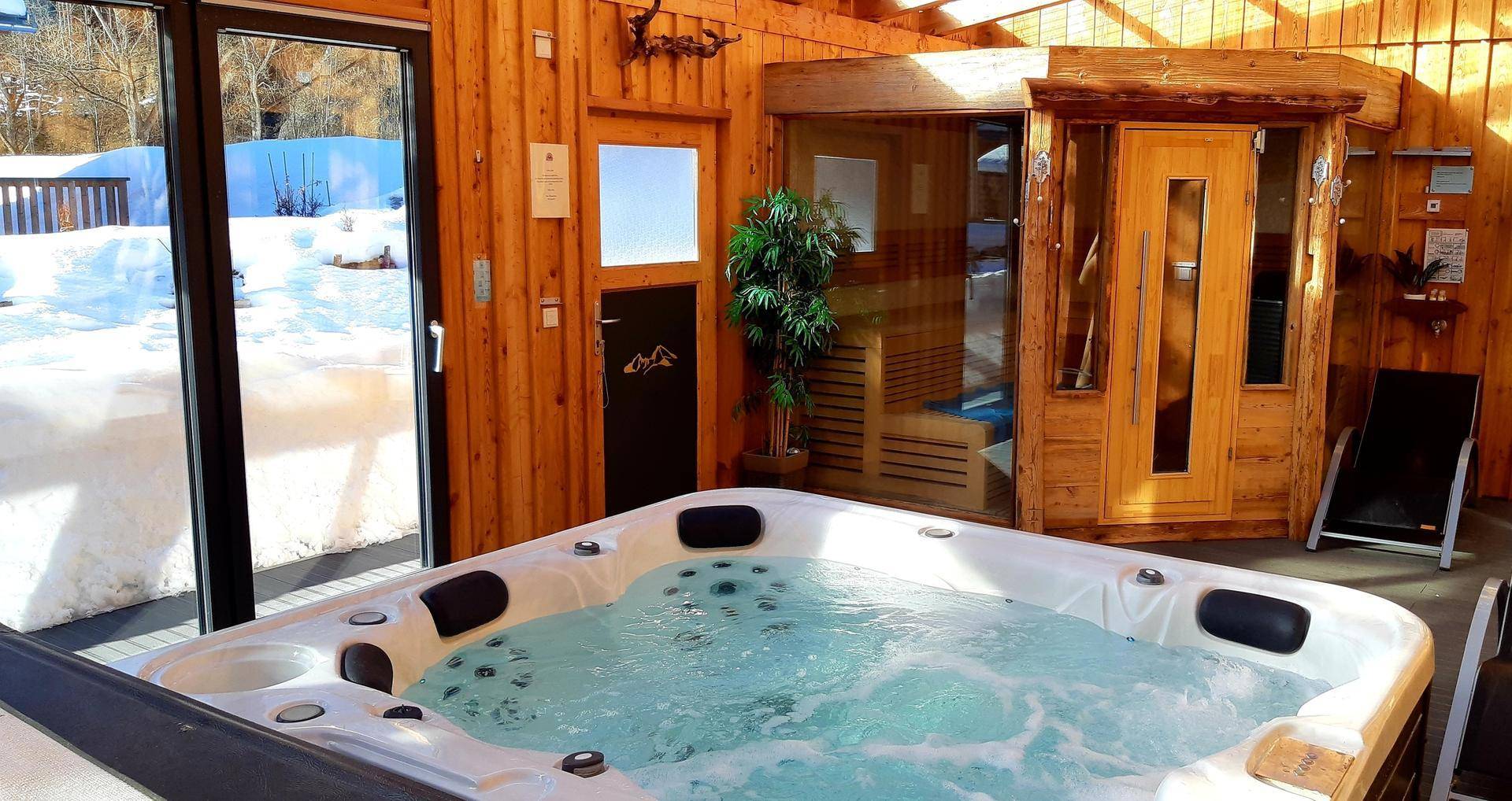 Exklusiver Wellnessbereich mit sprudelndem Whirlpool und angrenzender Holzsauna.