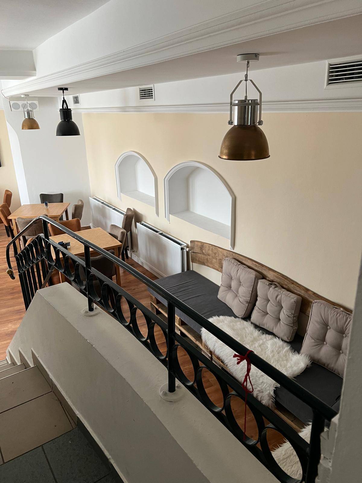 Blick von der Treppe in den Loungebereich mit Palettensofas, Geländer und modernen Hängelampen.