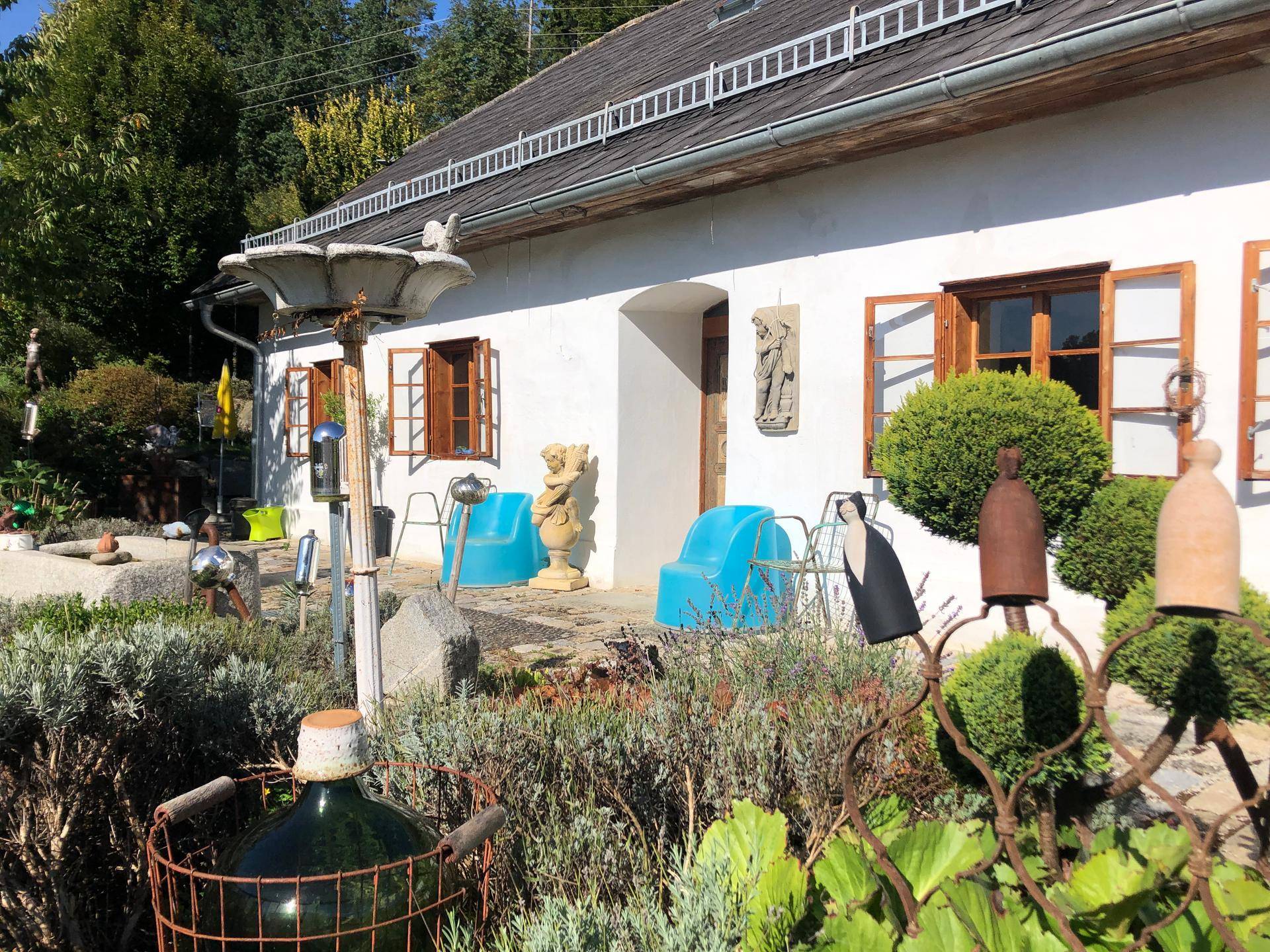 Charmante Hausfassade mit blauen Sitzgelegenheiten und einem liebevoll gestalteten Gartenbereich.