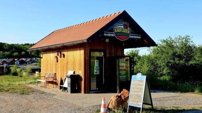 Kleiner Laden mit Holzausstattung und Satteldach in ländlicher Umgebung.