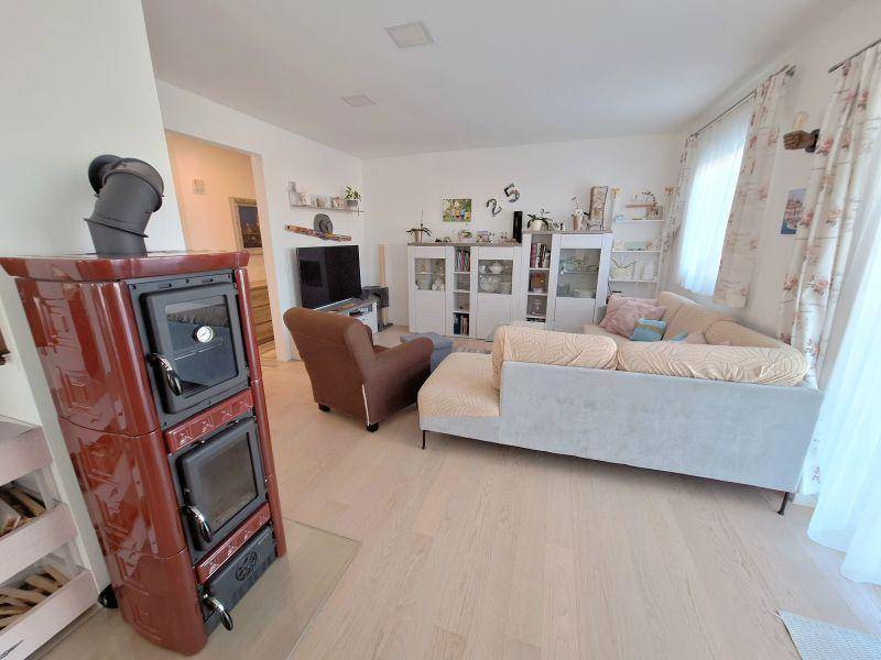Gemütliches Wohnzimmer mit Kachelofen, hellem Holzboden und moderner Dekoration.