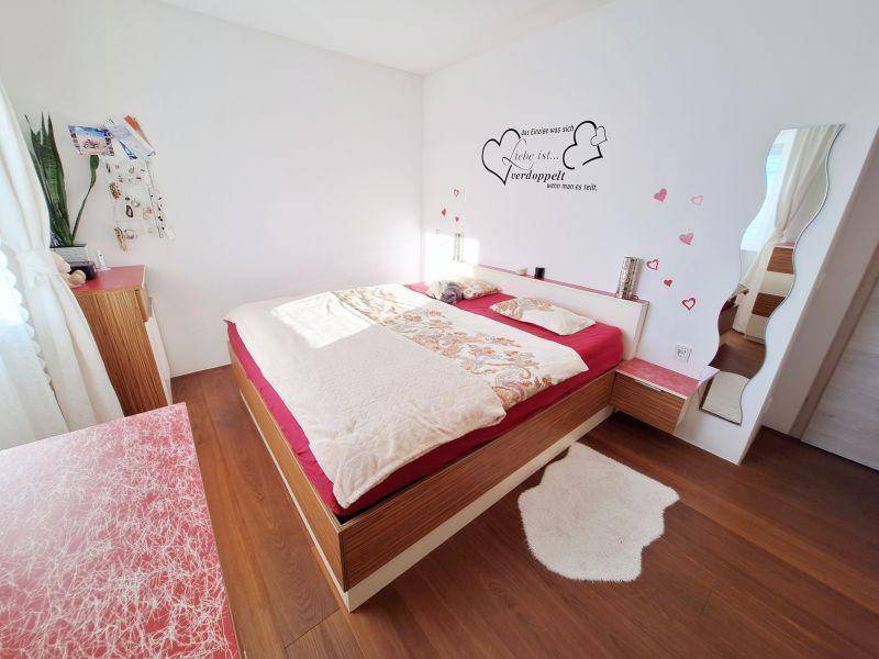 Gemütliches Schlafzimmer mit Doppelbett, Holzboden und dekorativer Wandgestaltung.