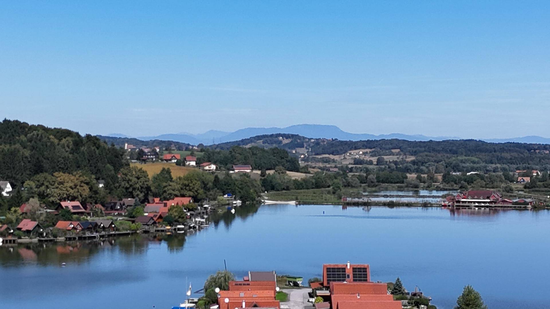 Weitläufiger Blick über den See mit fernen Bergen und ländlicher Umgebung.