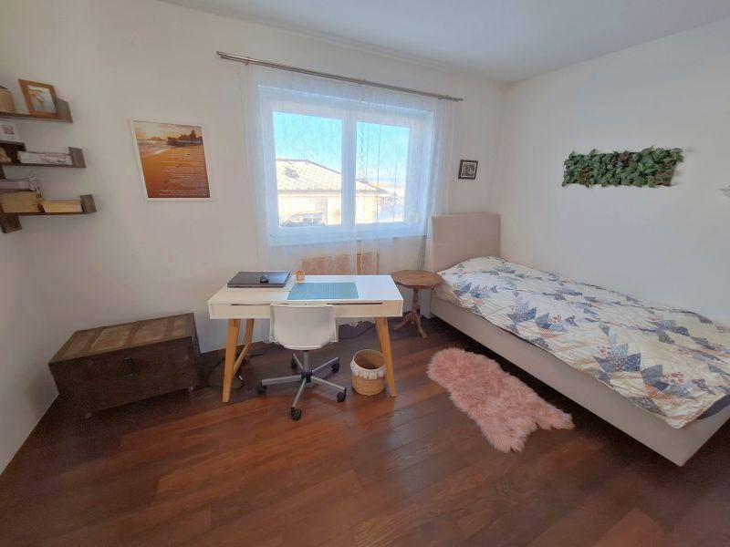 Helles Schlafzimmer mit Einzelbett, Schreibtisch und Holzboden.