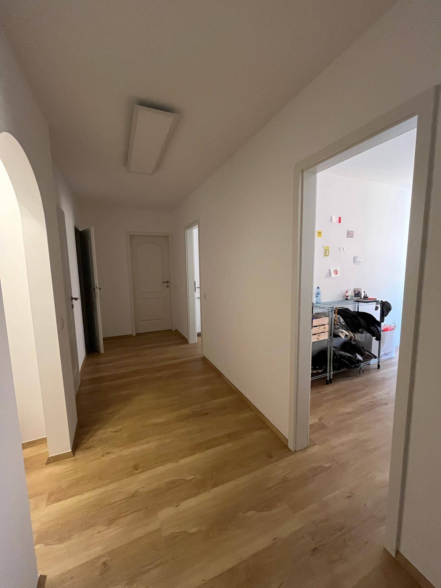 Langer, heller Flur mit Holzboden, der zu verschiedenen Räumen der Wohnung führt.