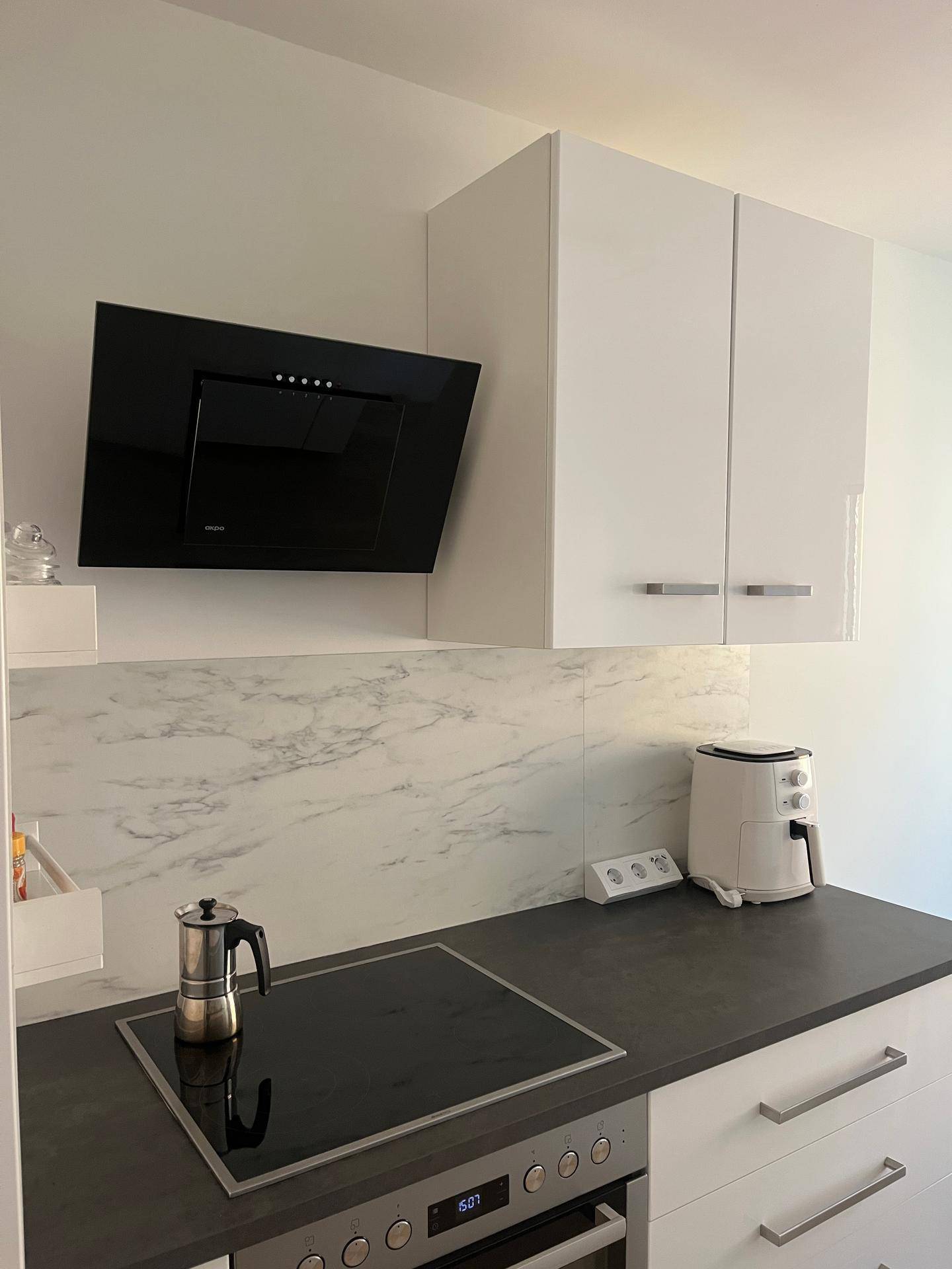 Induktionskochfeld mit integriertem Backofen und moderner schwarzer Dunstabzugshaube in der Küche.